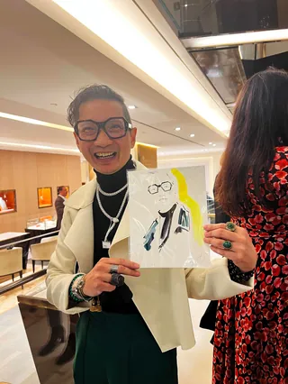 Person smiling and holding a fashion sketch at Bulgari event by Elise Lee Live Event Drawing