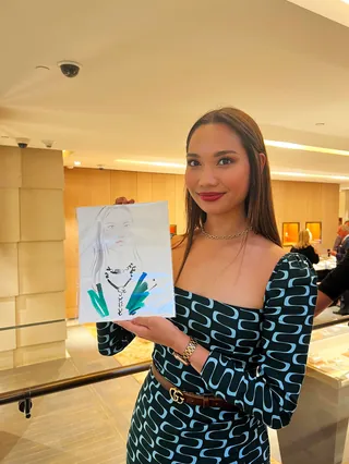 Woman in patterned dress holding a portrait drawing by Elise Lee