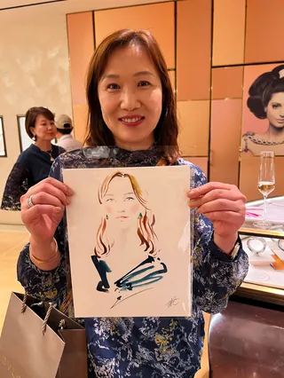Woman showing a caricature portrait at a Bulgari live event by Elise Lee
