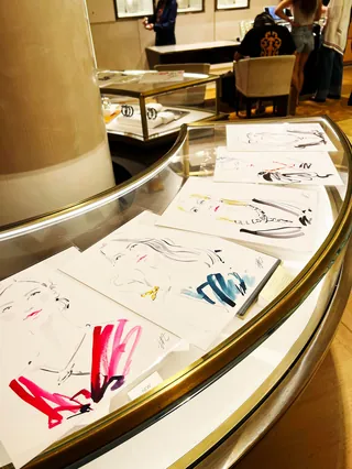 Fashion sketches displayed on curved glass table by Elise Lee