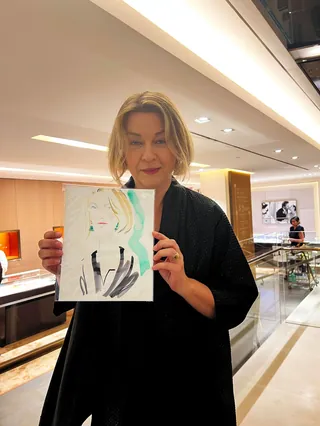 Woman displaying a fashion illustration in a luxury boutique by Elise Lee
