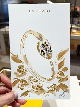 Hand holding Bulgari gold serpent-themed bracelet illustration