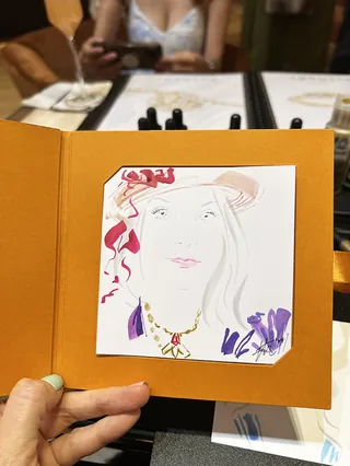Hand holding a card with a colorful fashion illustration of a woman
