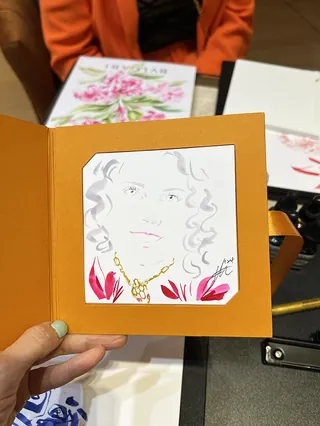 Hand holding floral portrait artwork with pink and gold details