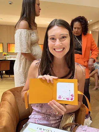 Smiling woman holding a card at Bulgari Mother's Day event