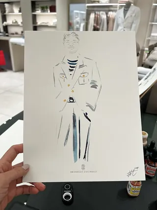 Hand holding a fashion illustration of a man in blazer and striped shirt