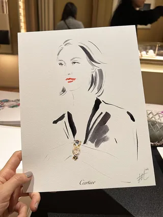 Hand holding fashion illustration with necklace at Cartier event
