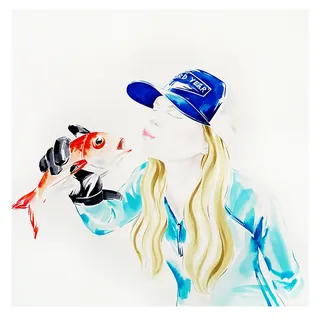 Woman in cap holding and kissing a red fish