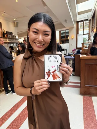 Woman smiling and holding a live event sketch by Elise Lee