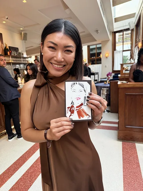 Woman smiling and holding a live event sketch by Elise Lee