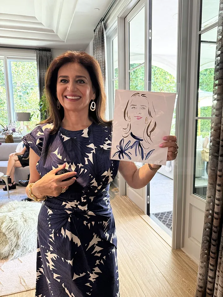 Woman smiling and holding a live portrait drawing by Elise Lee
