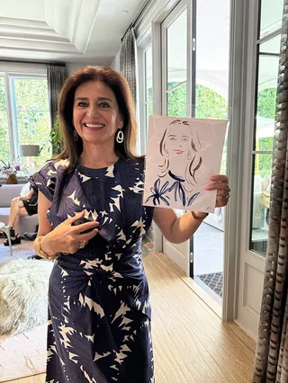 Woman smiling and holding a live portrait drawing by Elise Lee