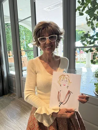 Woman smiling and holding a caricature drawing by Elise Lee