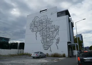 Large mural map on building wall by Ellie Compton with cars in foreground