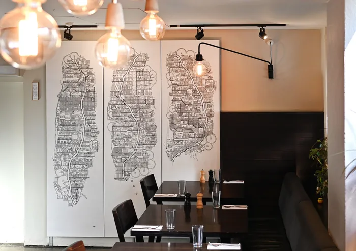 Modern restaurant interior with black and white wall art and hanging lights by Ellie Compton
