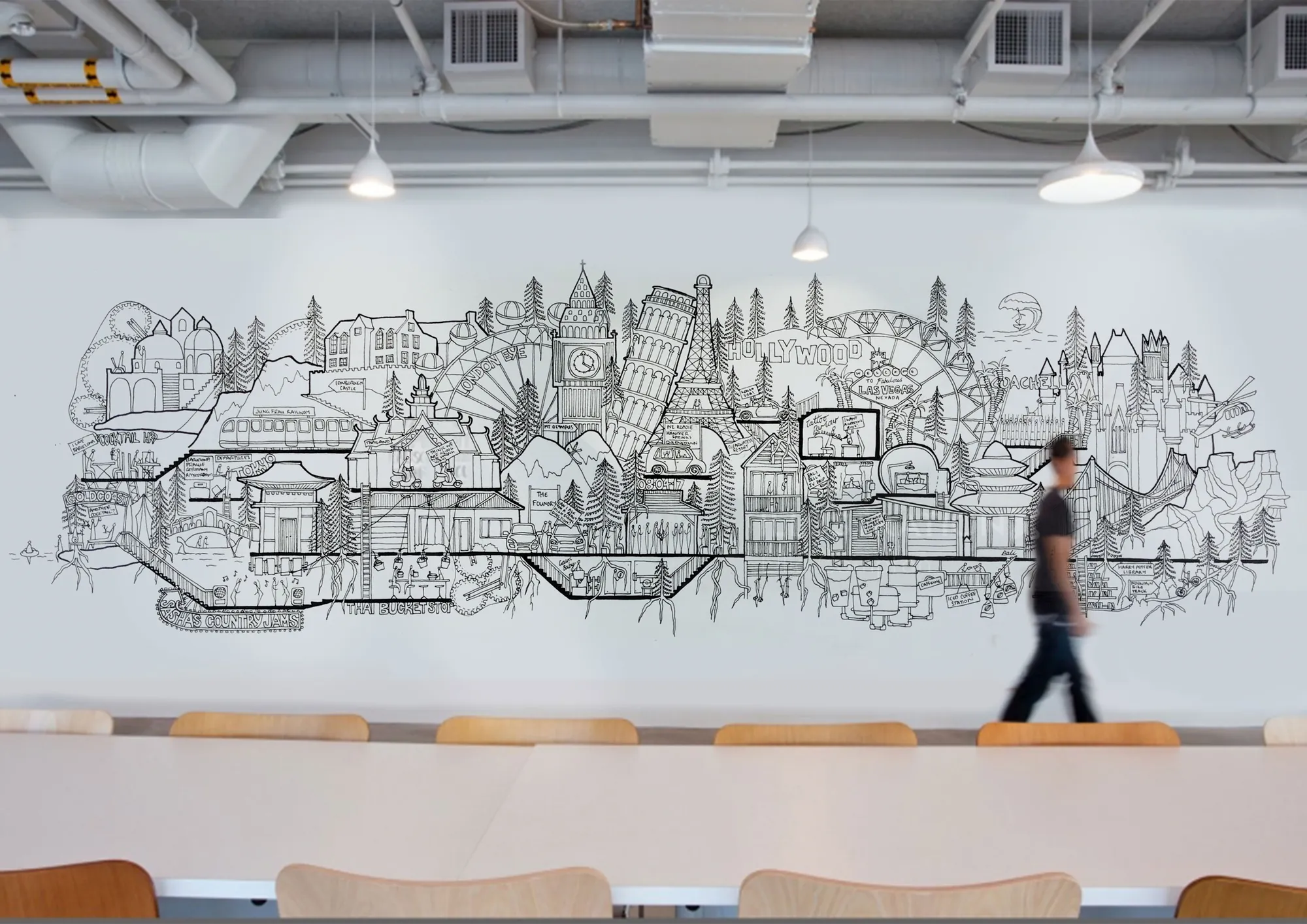 Cityscape mural in black and white on wall with person walking by, artist Ellie Compton