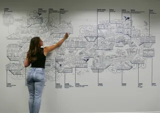 Woman pointing at detailed map on wall by Ellie Compton