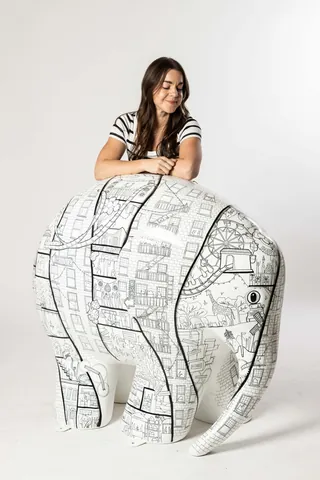 Woman with large white elephant sculpture featuring black drawings