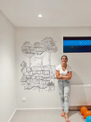 Woman posing beside detailed black and white mural on white wall