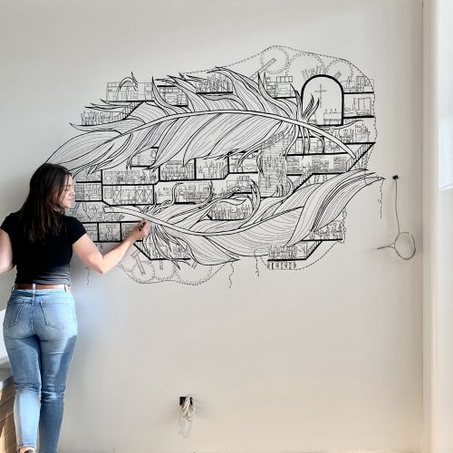 Artist creating black and white abstract feather mural on wall
