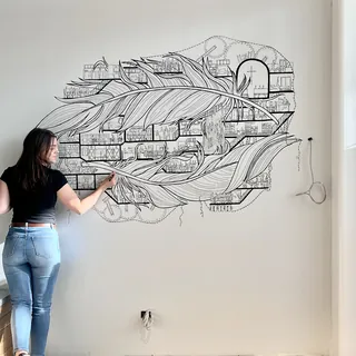 Artist creating black and white abstract feather mural on wall