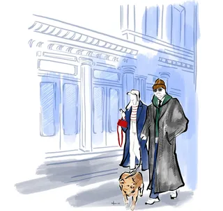 Two people walking a dog on a city street with tall buildings