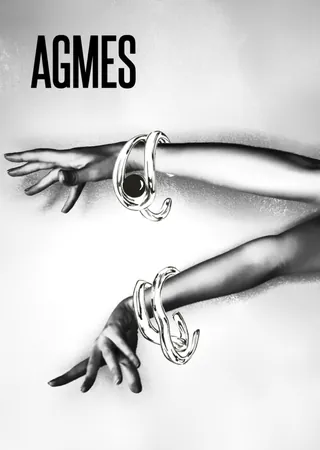 Two arms wearing silver bracelets with AGMES logo in black and white