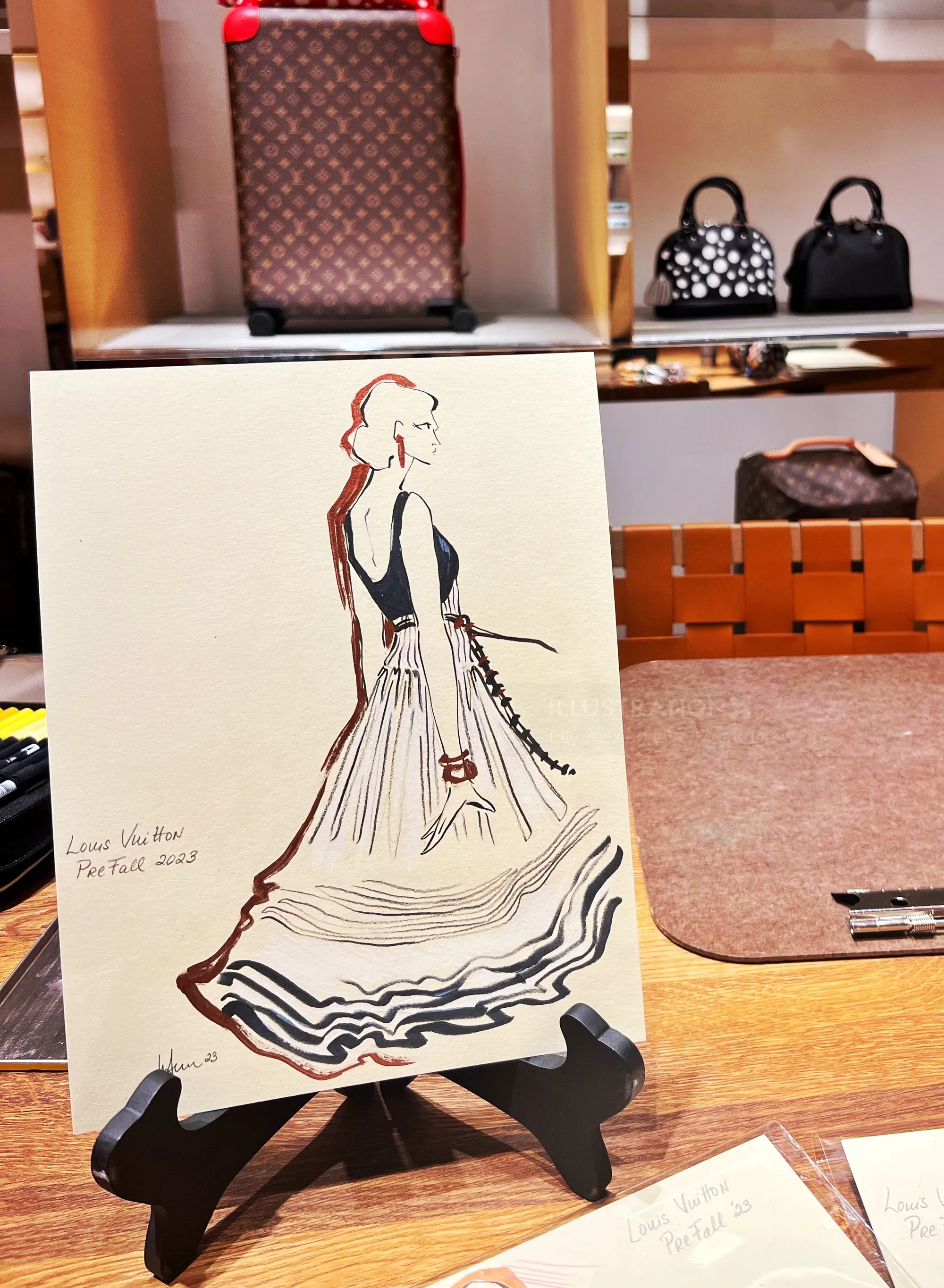 Ilustración de moda de una mujer con un vestido vaporoso en un soporte de exhibición junto a Elly Azizian