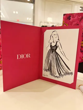 Fashion sketch of woman in dress inside red Dior folder by Elly Azizian