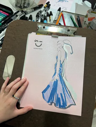Fashion sketch of blue gown on clipboard by Elly Azizian