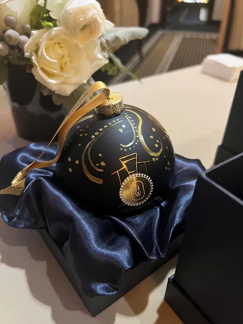 Black Christmas ornament with gold music notes next to white roses