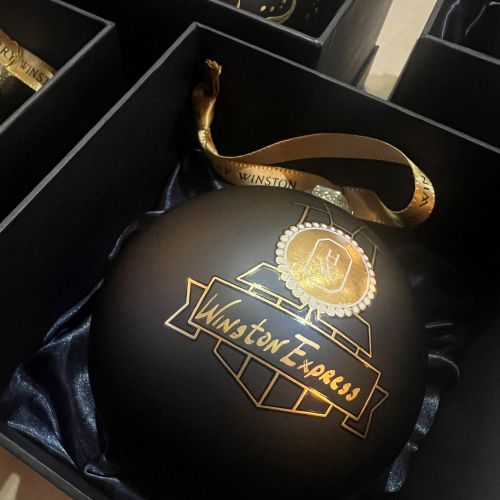 Black Christmas ornament with gold Winston Express logo and ribbon.
