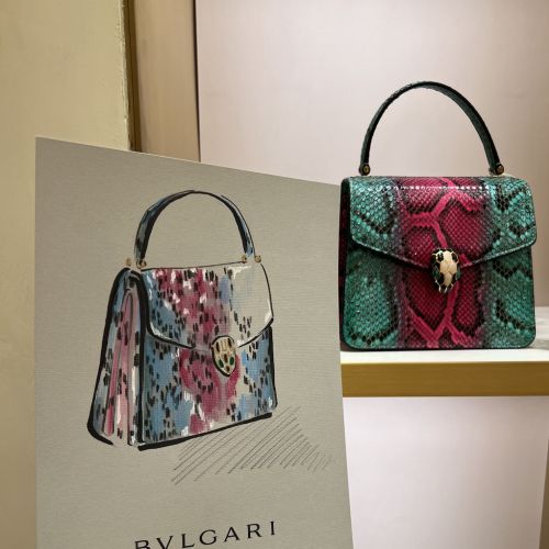 Hand holding Bvlgari handbag illustration with real handbag behind