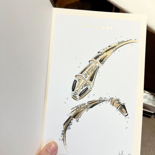 Hand holding card with abstract gold and black futuristic shapes artwork.