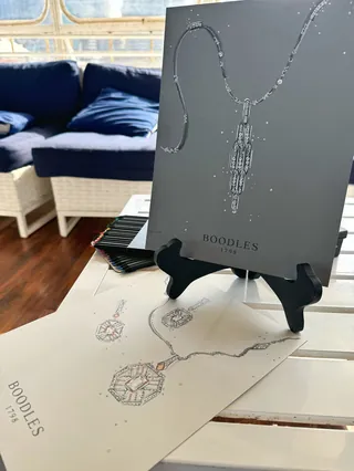 Boodles necklaces displayed on gray stand with sofa background
