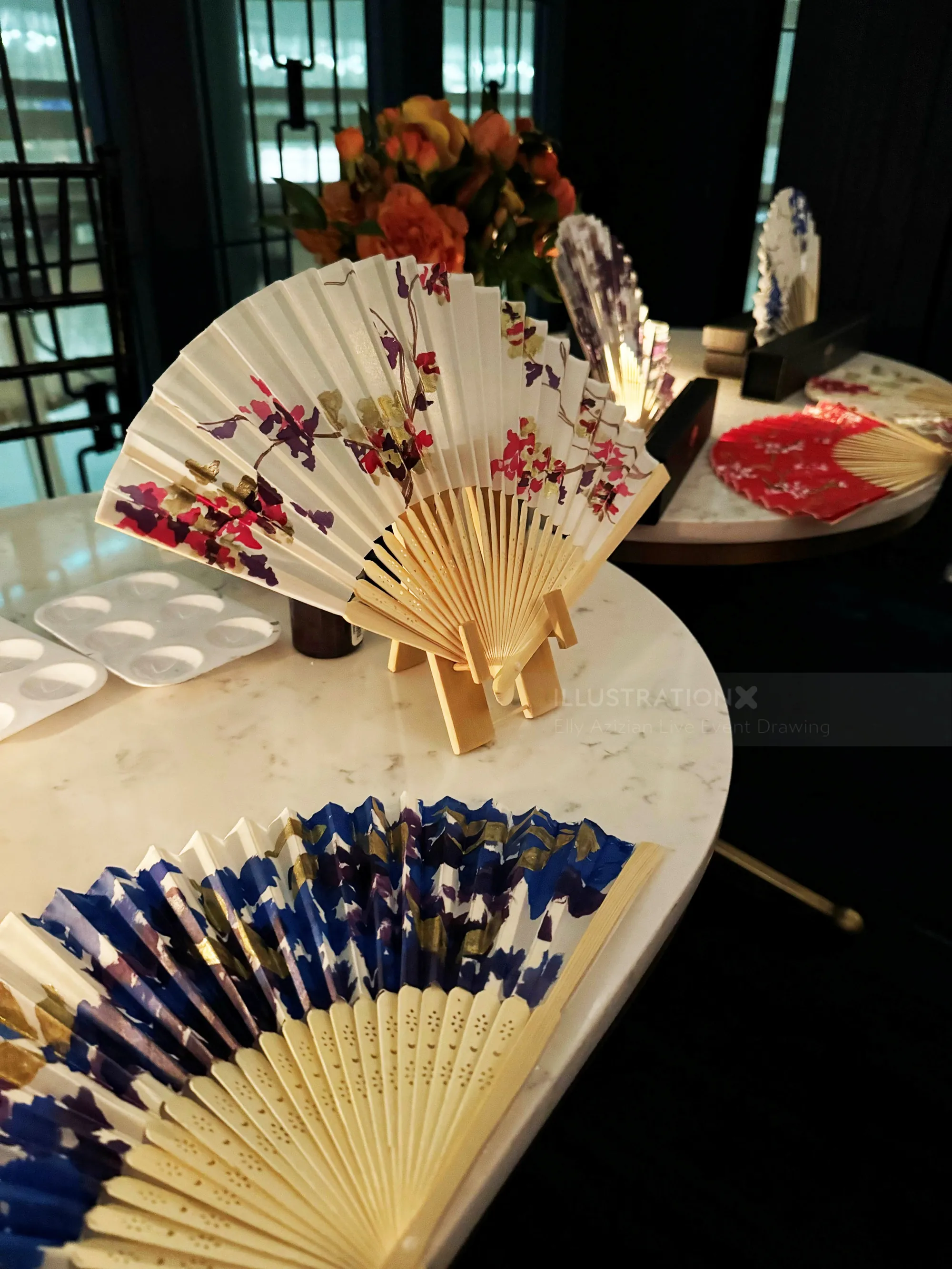 Various decorative hand fans with floral designs on a table