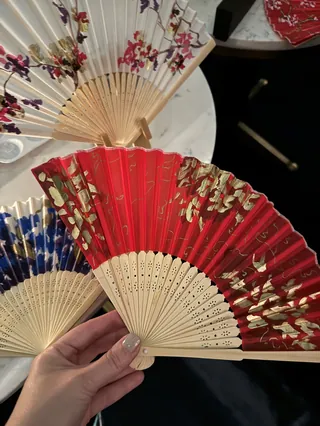 Hand holding decorative red floral folding fan among other fans