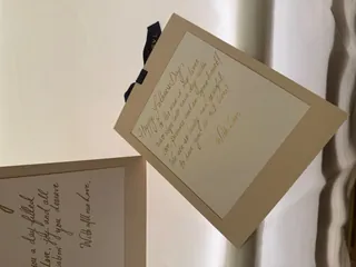 Two cream papers with handwritten cursive notes on a white surface.