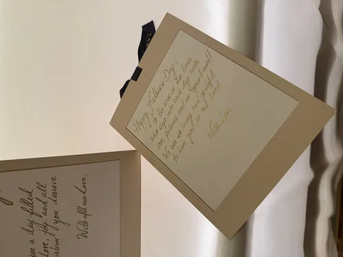 Two cream papers with handwritten cursive notes on a white surface.