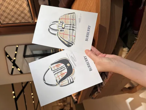 Hand holding two Burberry tote bag drawings by Elly Azizian