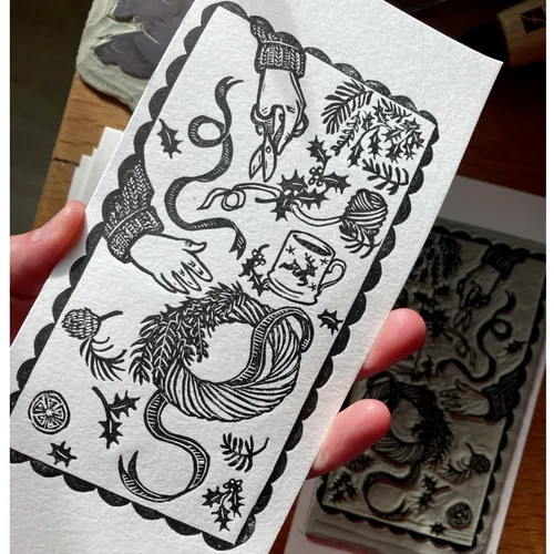 Black and white lino cut showing hands making a Christmas wreath, by Emily Robertson