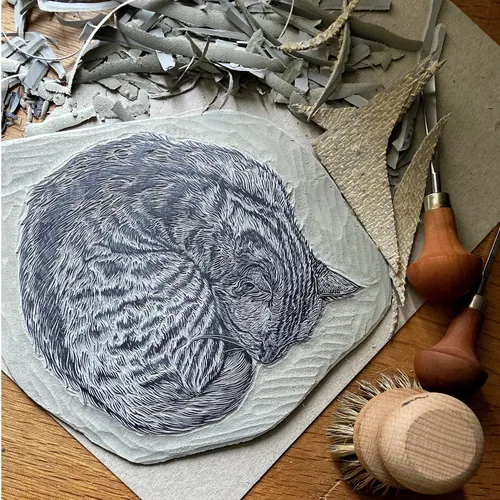 Lino block print of sleeping cat with carving tools by Emily Robertson
