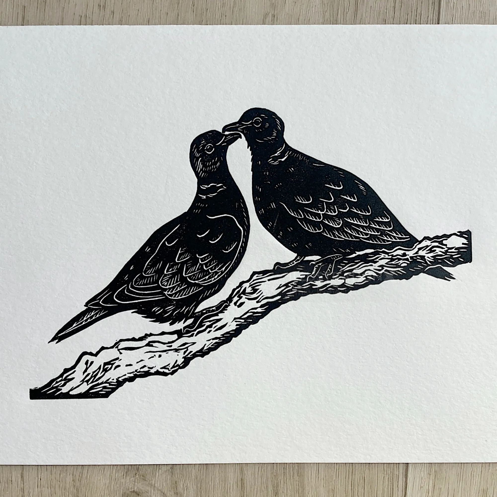 Black lino cut of two turtle doves on a branch by Emily Robertson