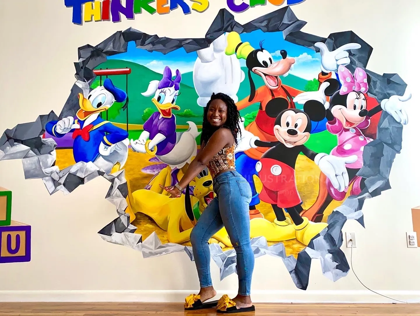Woman posing by Disney characters mural on wall by Esther Stimphat