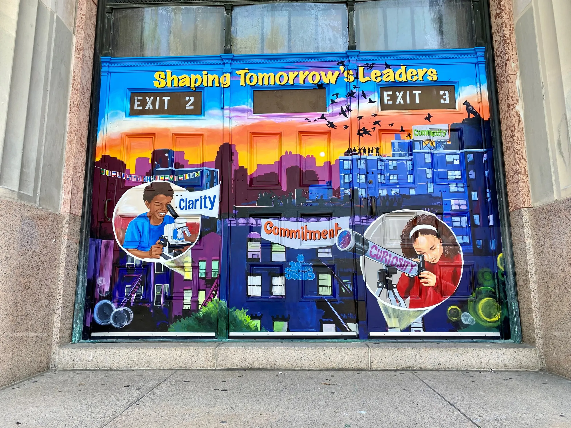 Mural showing cityscape and children learning, by Esther Stimphat