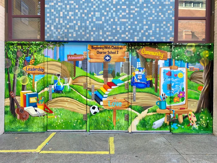 Colorful outdoor mural featuring books, signs, and nature elements