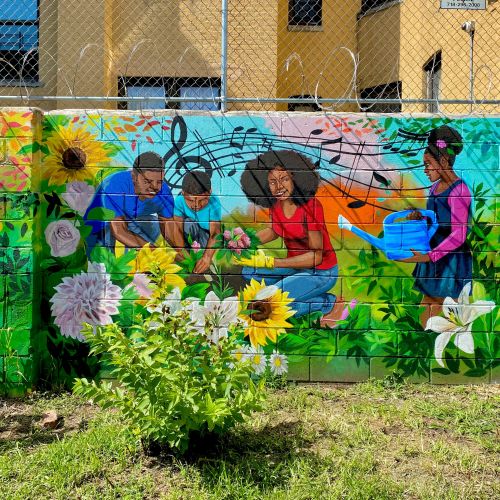 Mural of people gardening with sunflowers and musical notes on brick wall