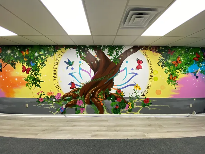 Mural featuring a large tree, butterflies, flowers, and inspirational quotes.