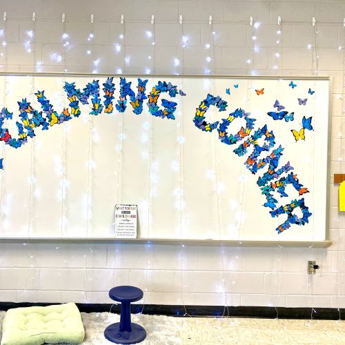 Whiteboard with 'The Learning Garden' spelled by butterfly decorations and string lights