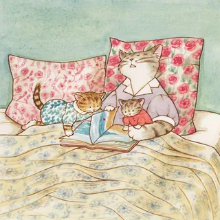 Cat parent reading a book to two kittens on a bed with floral pillows